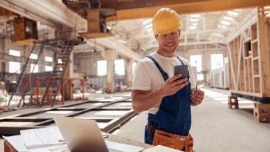 Top 7 des meilleurs téléphones de chantier en 2022 cheerful builder using smartphone at construction site
